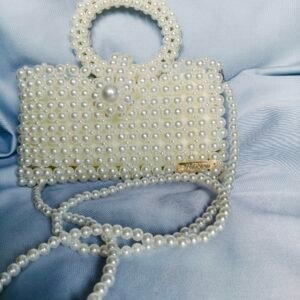 Borsa a perline color avorio con manico tondo, maxi perla e tracolla lunga su sfondo raso